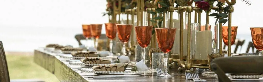 orange wine glass crystal clear plates and light brown table napkins with white rose inside and silver silver ware