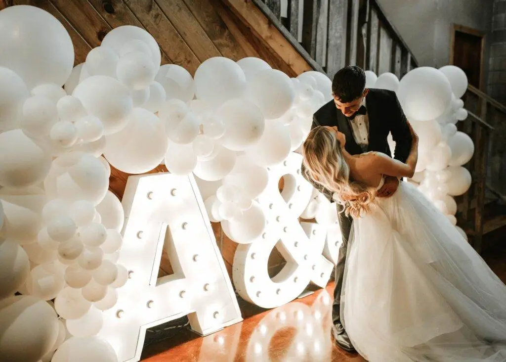 Groom and Bride with white balloons and their initials behind them