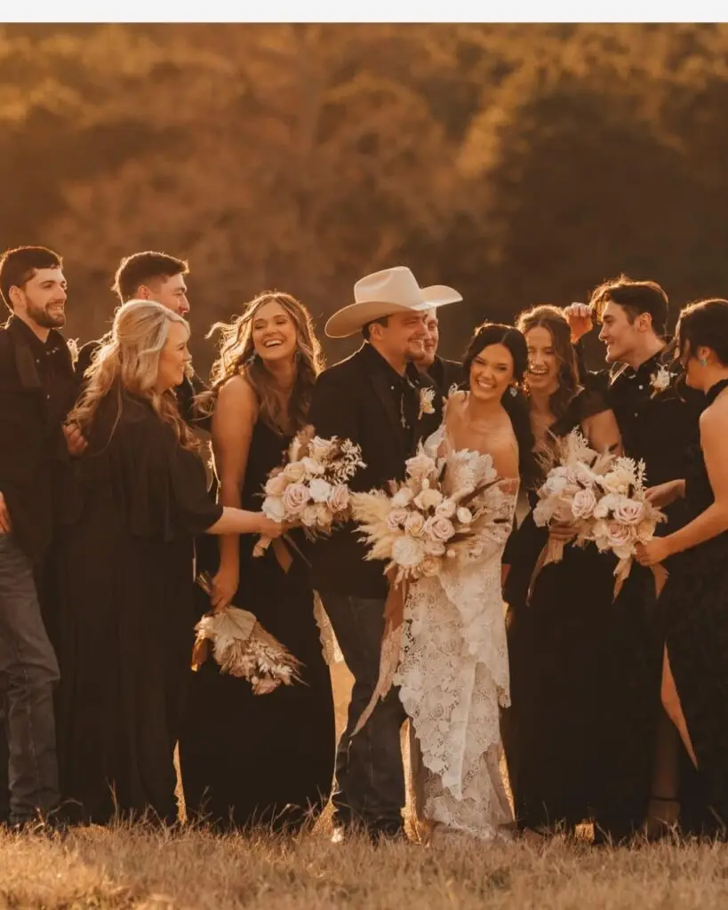At El Cerrito, a joyful wedding party in black attire poses with bouquets outdoors, smiling amid natural light and elegant scenery.